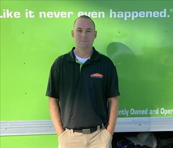 Male standing behind a green truck.